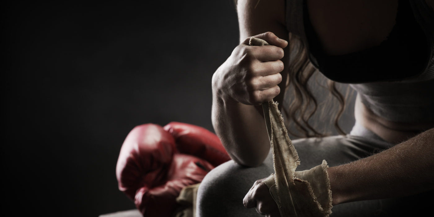 Woman boxer wrapping bandage around hand prior to game