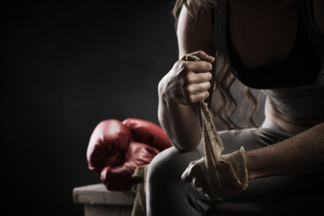 Woman boxer wrapping bandage around hand prior to game
