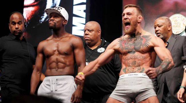 Undefeated boxer Floyd Mayweather Jr. (L) of the U.S. and UFC lightweight champion Conor McGregor of Ireland pose during their official weigh-in at T-Mobile Arena in Las Vegas